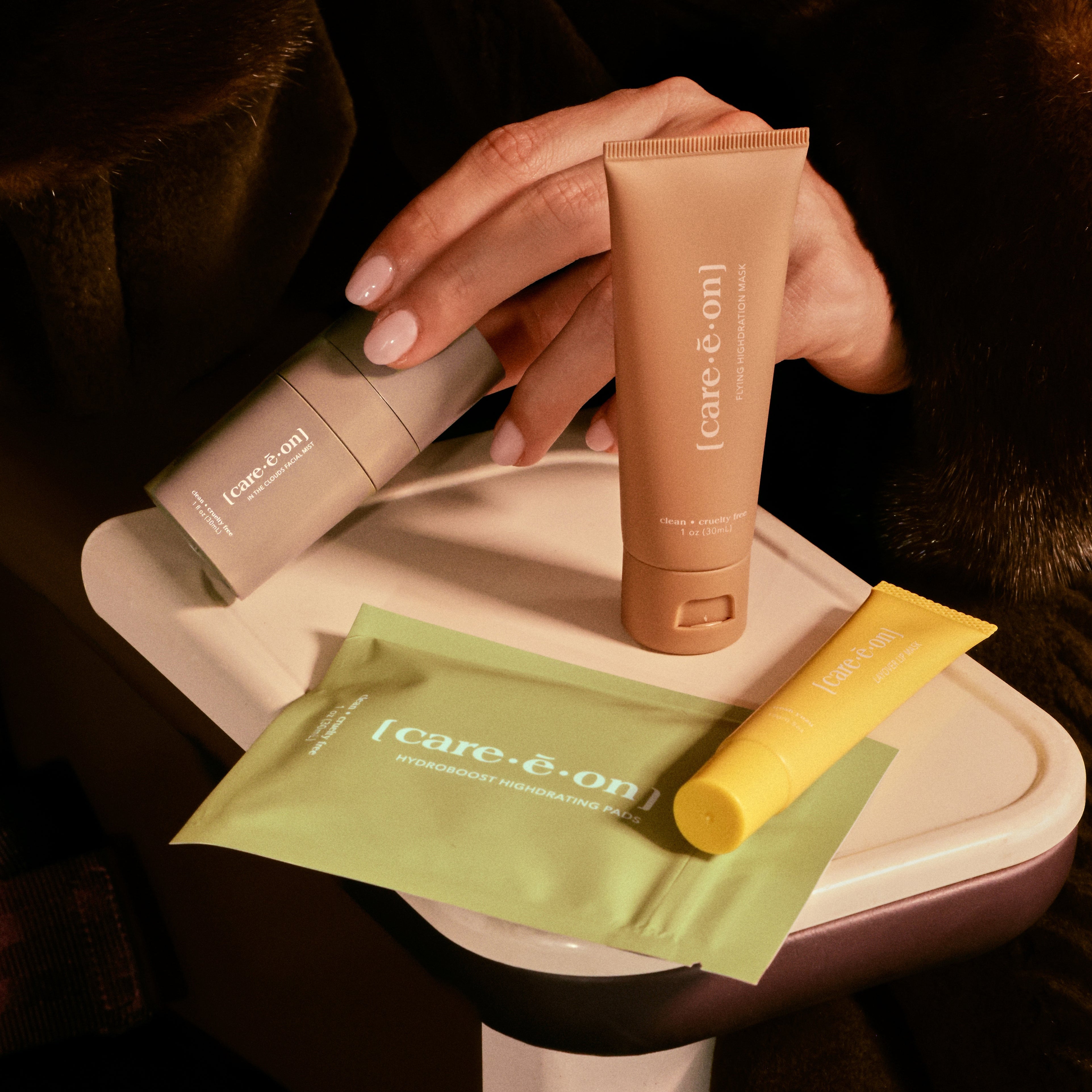 Person holding skincare products on a white tray with a dark background