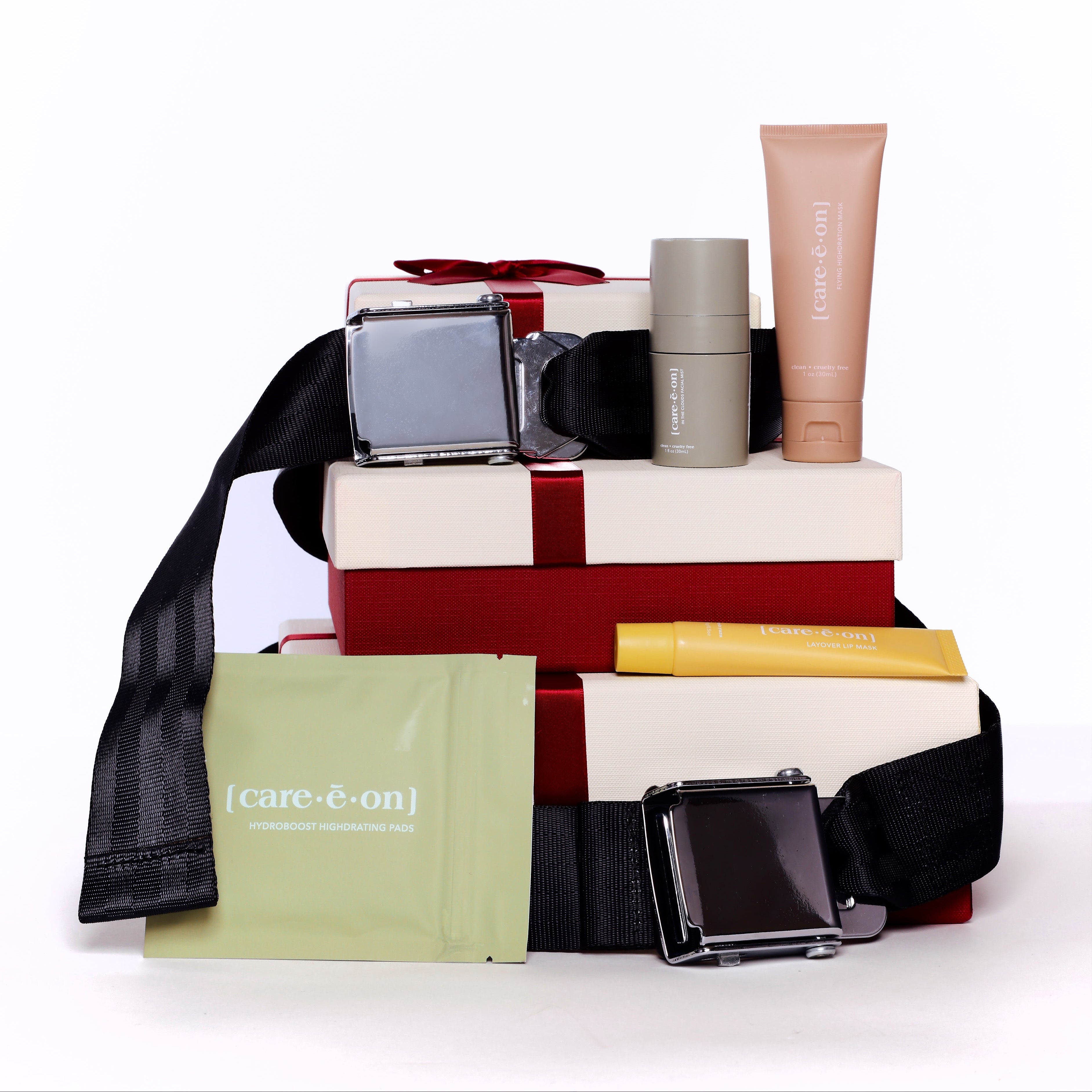 Stack of beauty products including a perfume bottle, lipsticks, and a tube on a white background.