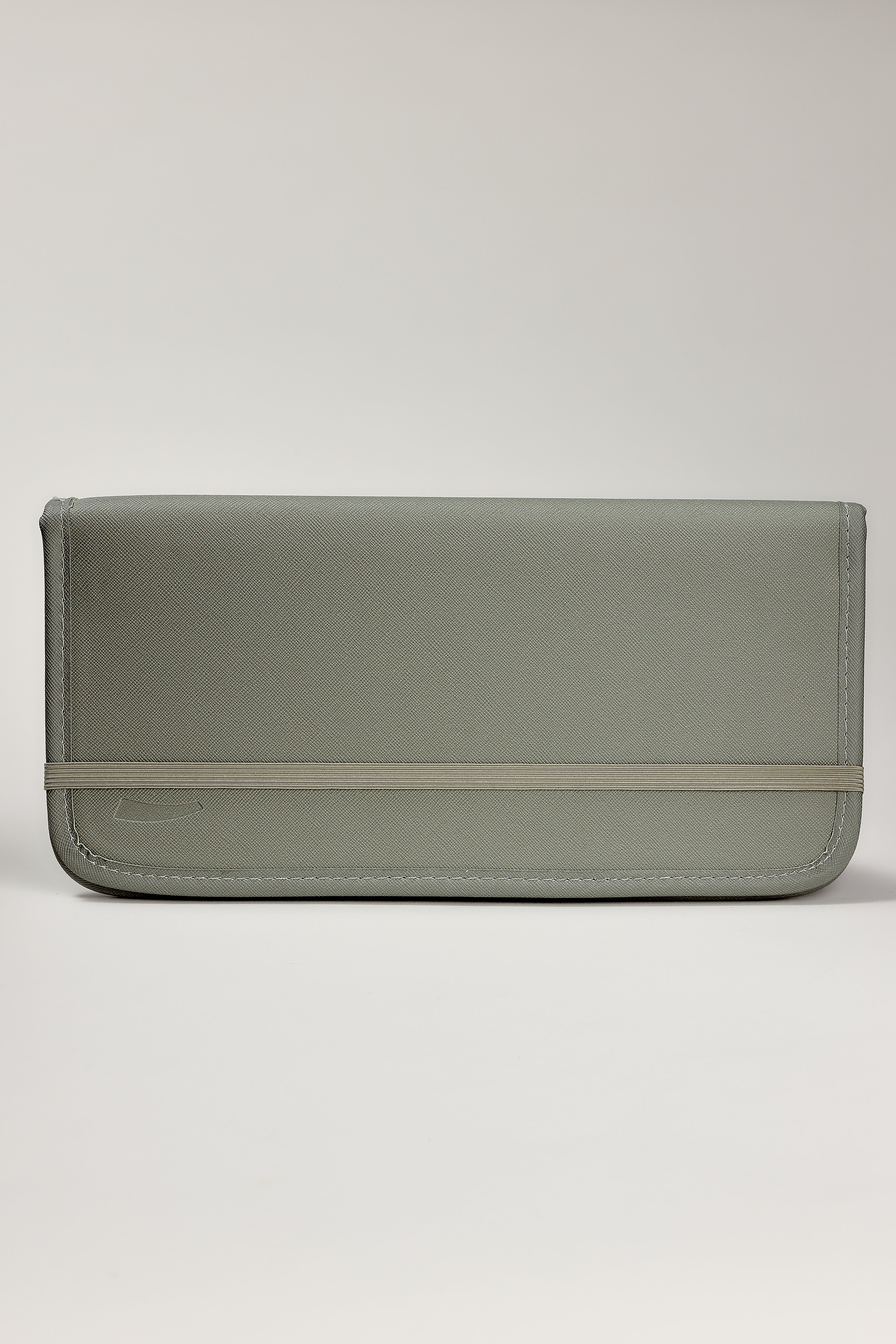 A sage green leather clutch organizer with a horizontal elastic band detail across the front, shown against a neutral light gray background.