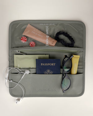 Care.ē.on Carry-All travel organizer packed with skincare, passport, glasses, headphones, and other travel essentials.