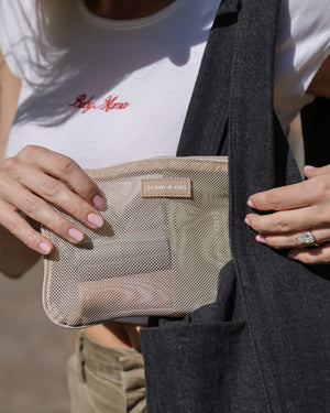 Care.ē.on En Route Essentials Kit mesh bag being packed into a travel bag.