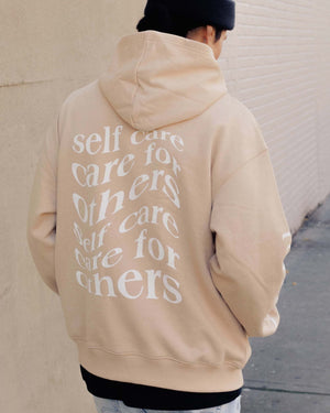 Back view of the Care.ē.on En Route Hoodie showing the white Care for Others, Self Care graphic.