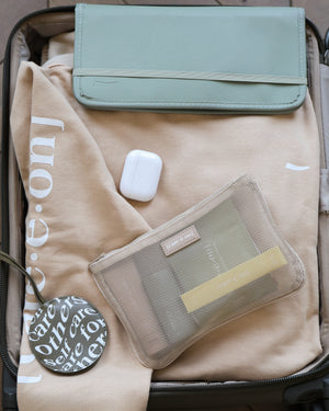 Care.ē.on En Route Hoodie packed in a suitcase with travel essentials.