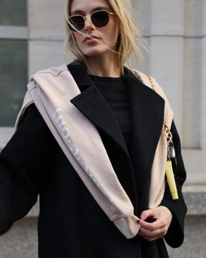 Woman wearing the Care.ē.on En Route Hoodie layered over her shoulders while traveling.