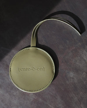 Back of the green Care.ē.on Vegan Voyage Luggage Tag with embossed logo and adjustable strap.